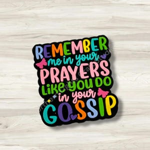 May include: A black, rectangular sticker with the text "REMEMBER me in your PRAYERS like you DO in your GOSSIP" in various colors. The sticker has a butterfly graphic and a heart graphic.