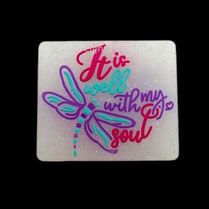 May include: White square with glitter background featuring a purple dragonfly with turquoise accents. The text "It is well with my soul" is written in pink and purple.