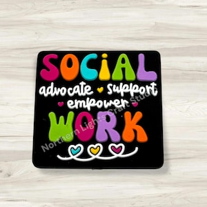 May include: A black square with the words "SOCIAL WORK" in colorful, bubble letters. The words "advocate, support, empower" are written in white script. The design includes hearts and the text "Northern Lights Craft Studio."