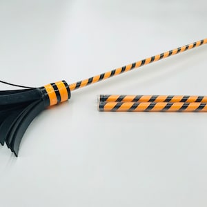 May include: A black and orange striped broom with a black rubber bristle head. The broom is made of two pieces, the handle and the bristle head.