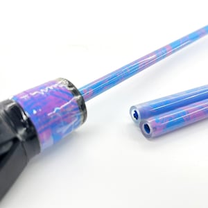 May include: Close-up of a tool with a black handle and a long, thin, blue and purple patterned shaft. Two additional shafts with the same pattern are next to it. The shafts have a hollow center.
