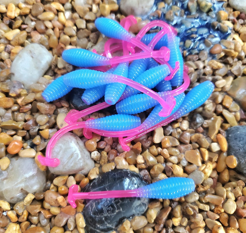 May include: A pile of blue and pink soft plastic fishing lures. The lures are shaped like worms and have a ribbed texture.