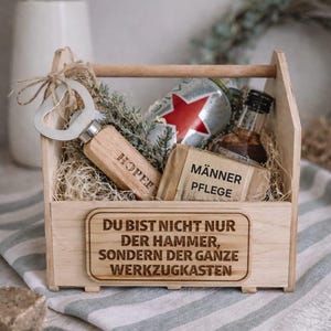 Könnte beinhalten: Ein hölzernes Werkzeugkasten-Geschenkset mit einem Flaschenöffner, einer Flasche Likör, einem Stück Seife und einer Bierdose. Auf dem Flaschenöffner steht "HOPE". Auf der Box steht der Text "DU BIST NICHT NUR DER HAMMER, SONDERN DER GANZE WERKZEUGKASTEN".