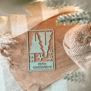 May include: A light green plastic Christmas tree and star-shaped cookie cutter with the words "Frohe Weihnachten" in a rectangular frame. The cutter is on a wooden cutting board.