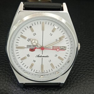May include: A silver Seiko 5 automatic watch with a white face. The watch features a black leather band, a day and date display, and luminous hands and markers. The watch face displays the text "SEIKO 5 Automatic" and "MADE IN JAPAN 6309".