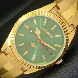 May include: A gold-tone Citizen wristwatch with a green face and gold-tone band. The watch face has gold-tone hour markers and a date window that reads "TUE 4".