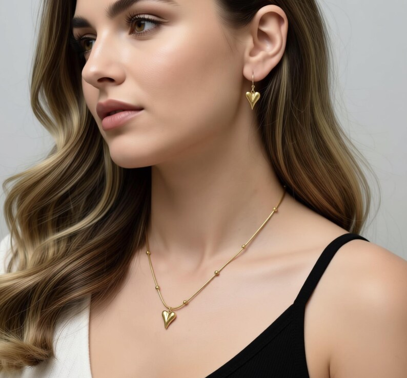 A woman with long, wavy hair wearing a gold necklace and earrings, looking to the side with a thoughtful expression.