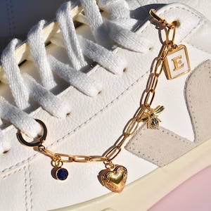 a white sneaker with a gold chain and heart charms