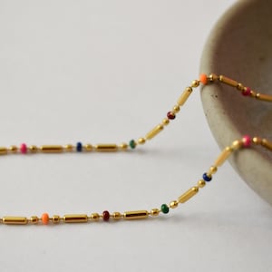 a long beaded necklace sitting next to a bowl