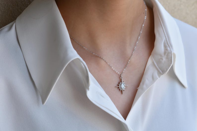 A close-up view of a person wearing a white collared shirt and a necklace with a pendant.