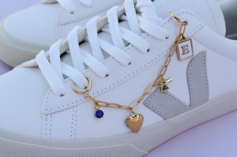 a white sneaker with a gold chain and charms