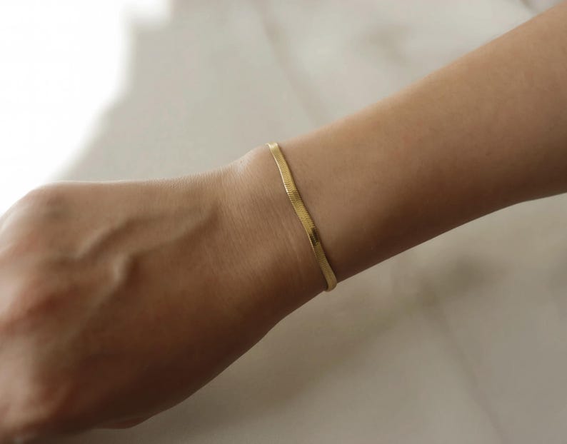 A gold bracelet is worn on a person's wrist.