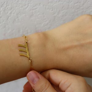 A person's wrist wearing two gold-colored bracelets with Chinese characters on them.