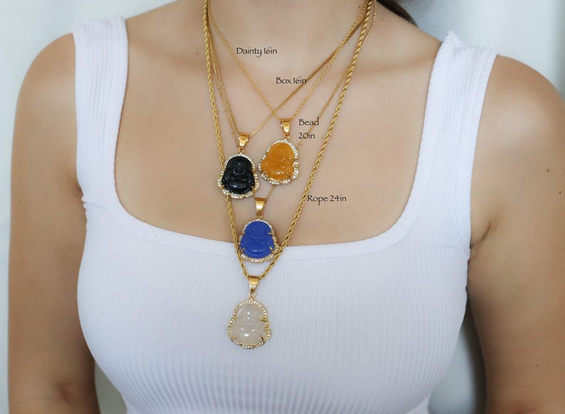 A woman wearing a white tank top with multiple necklaces around her neck.