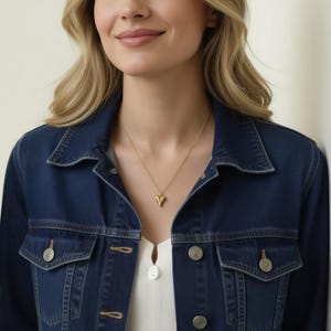 A woman wearing a blue denim jacket and a white top, smiling at the camera.