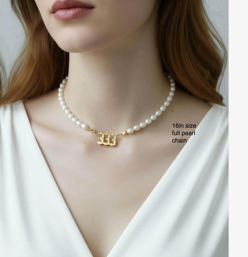 A close-up of a woman wearing a pearl necklace with a gold-colored pendant.