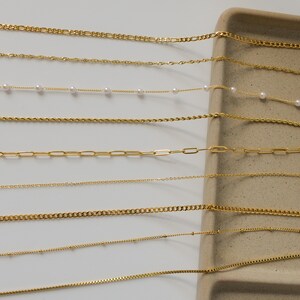a collection of various gold-colored necklaces arranged on a white surface.