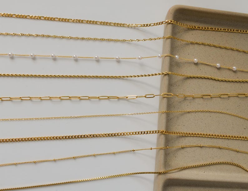 a collection of various gold-colored necklaces arranged on a white surface.