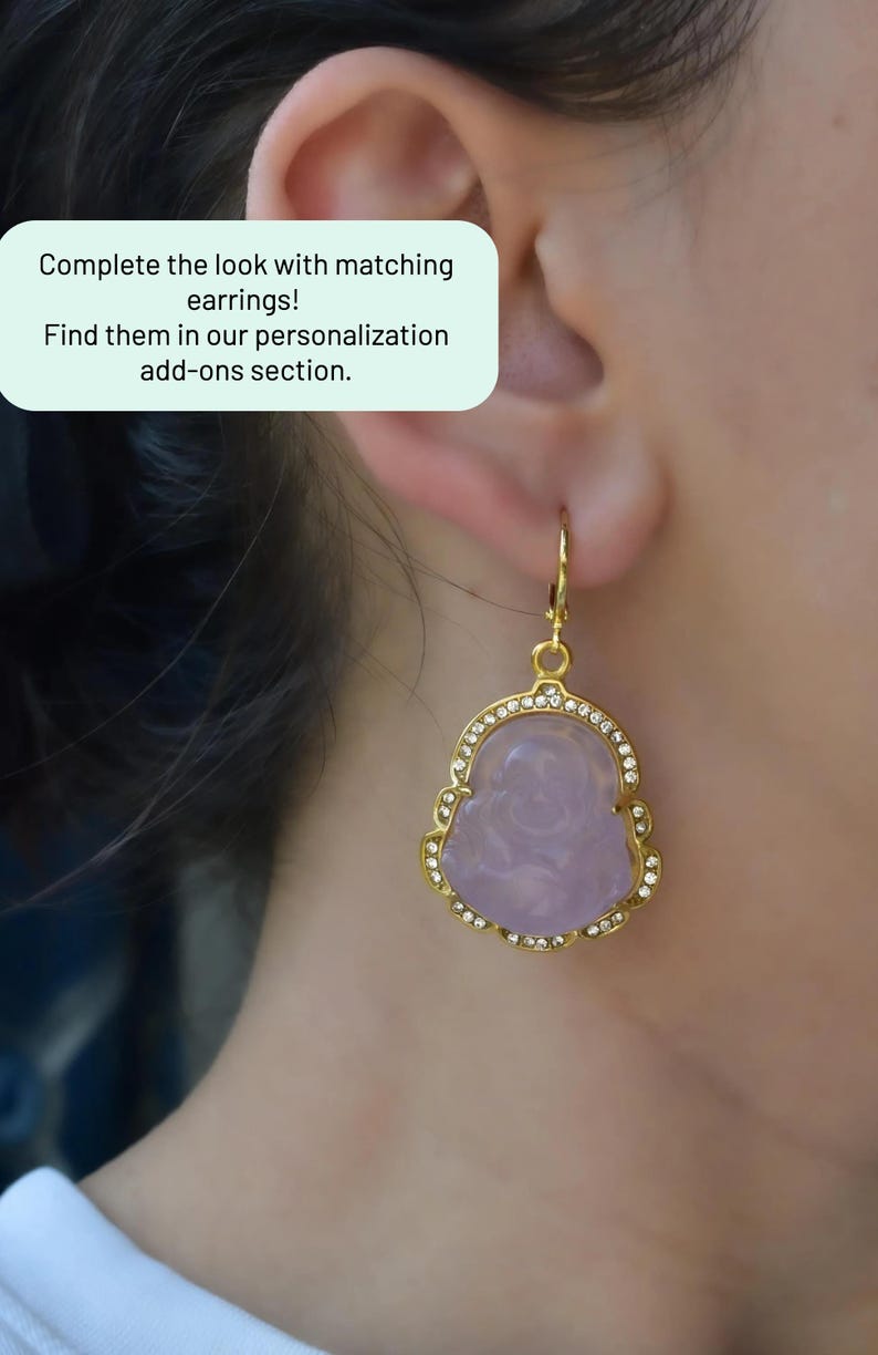 A close-up of a person's ear wearing a pair of gold earrings with a purple stone.
