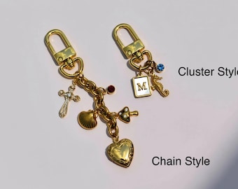 Pode incluir: Dois porta-chaves dourados com fechos de mosquetão. O estilo de corrente apresenta um relicário em forma de coração, uma concha, uma cruz e um pendente de cogumelo. O estilo de cacho inclui um pendente retangular com a letra M, um cavalo-marinho e um cristal azul.