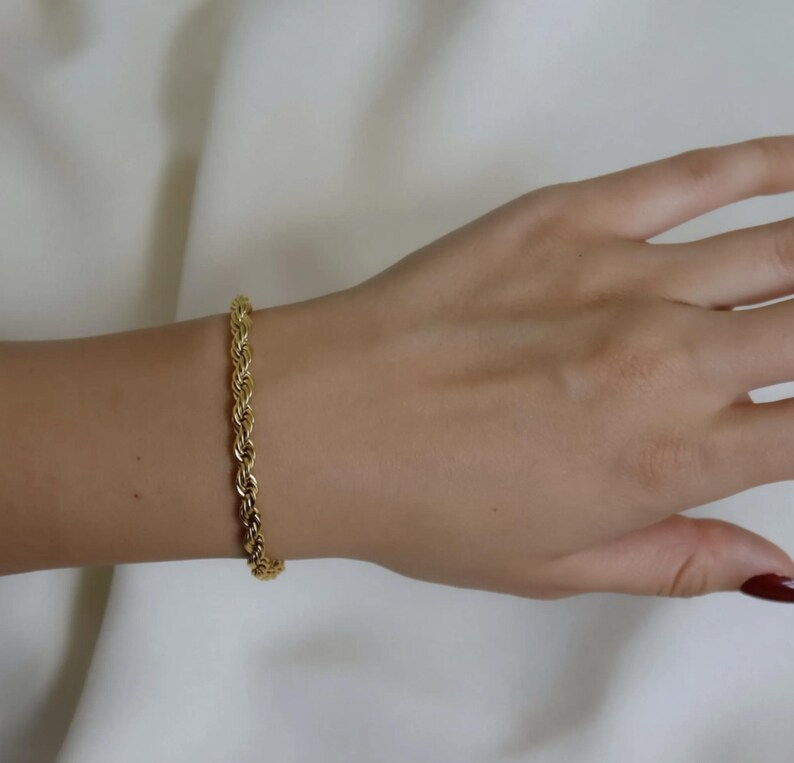 A gold bracelet is worn on a person's wrist.