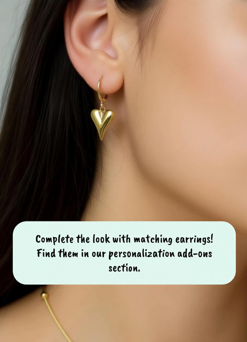 A close-up view of a person's ear adorned with a pair of gold heart-shaped earrings.