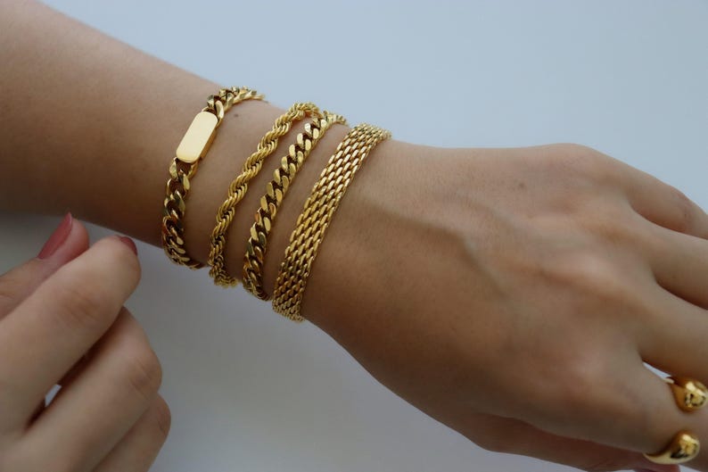 A close-up view of a person's wrist adorned with multiple gold bracelets.