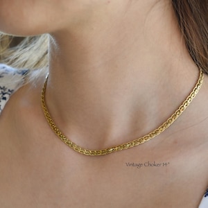 A close-up of a woman's neck and chest wearing a gold chain necklace.