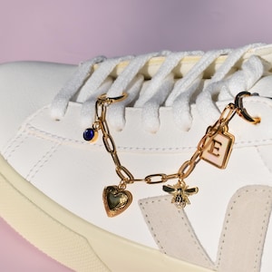 a white sneaker with a heart charm on a chain