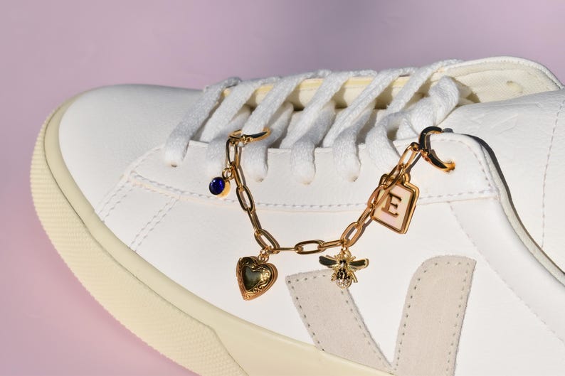 a white sneaker with a heart charm on a chain