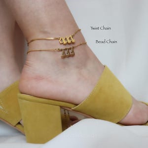 A close-up of a person's foot wearing yellow high-heeled sandals, with a gold ankle bracelet on the ankle.