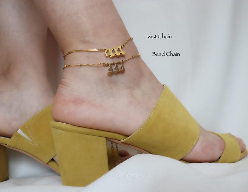 A close-up of a person's foot wearing yellow high-heeled sandals, with a gold ankle bracelet on the ankle.