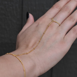 a woman's hand wearing a gold chain bracelet
