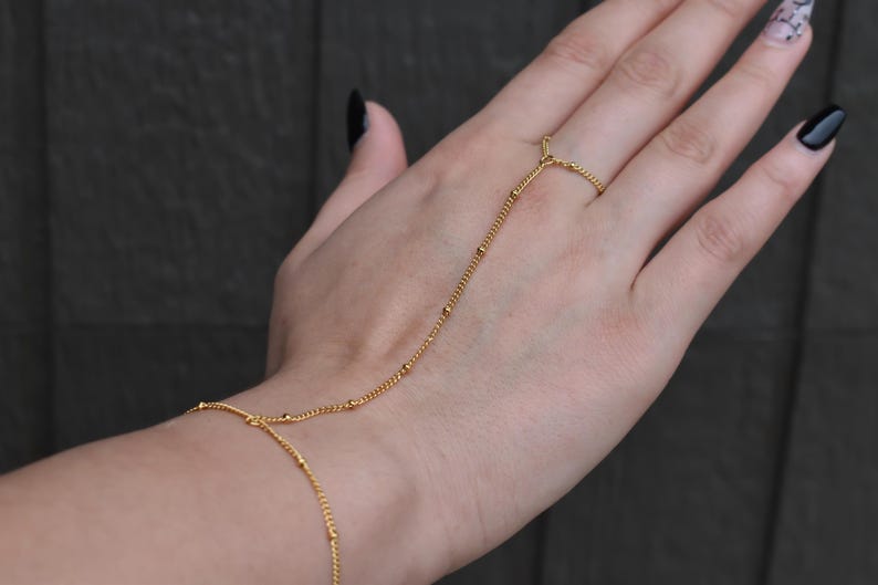 a woman's hand wearing a gold chain bracelet