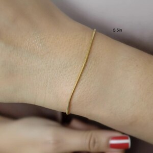 A close-up view of a person's wrist wearing a gold-colored bracelet.