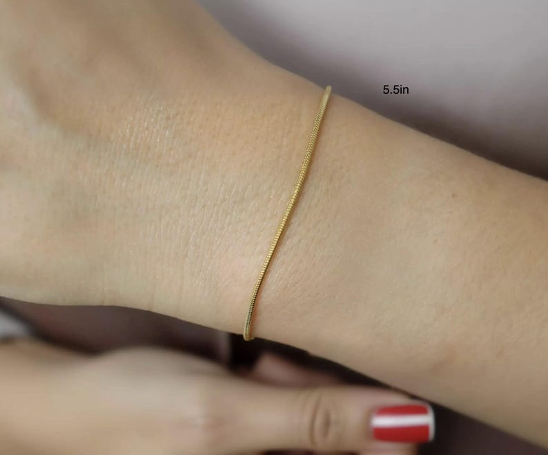 A close-up view of a person's wrist wearing a gold-colored bracelet.