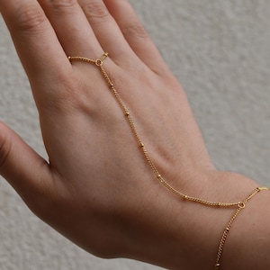 a woman's hand with a gold chain bracelet on it