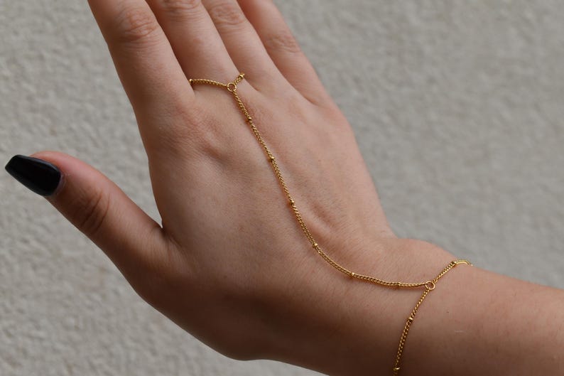 a woman's hand with a gold chain bracelet on it