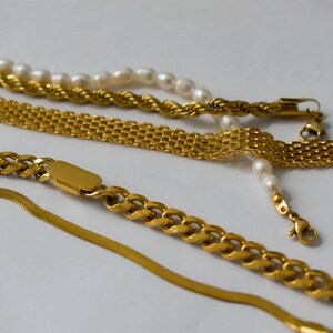 a collection of gold necklaces and bracelets arranged on a white background.