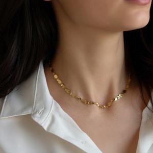 A close-up view of a gold necklace with small flower-shaped pendants around the person's neck.