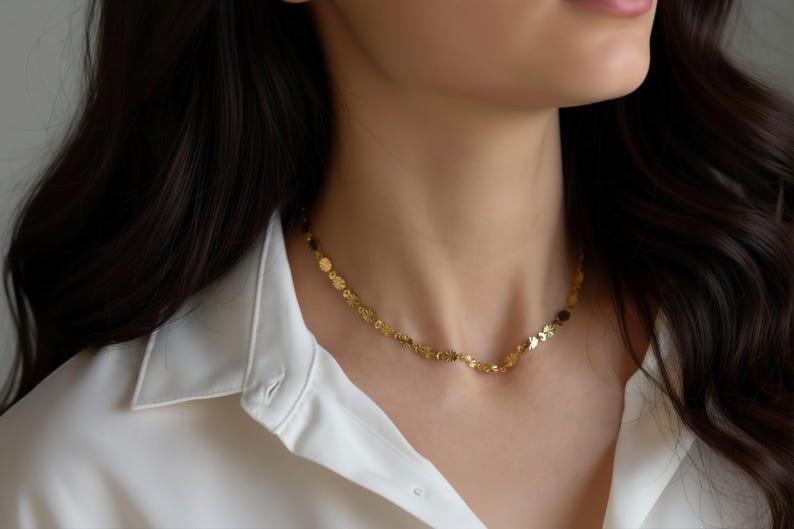 A close-up view of a gold necklace with small flower-shaped pendants around the person's neck.