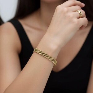 A close-up of a person's arm wearing a gold bracelet.