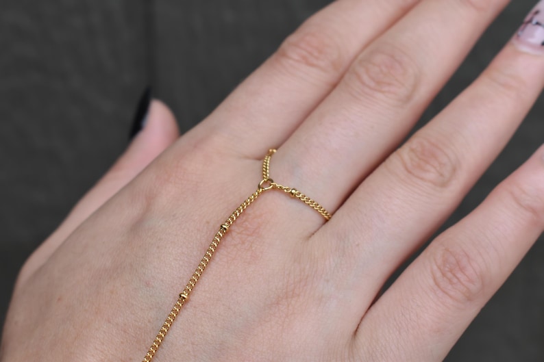 a woman's hand with a gold chain bracelet on it