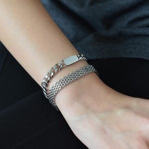 A close-up view of a person's wrist wearing a silver bracelet with a chain-link design.
