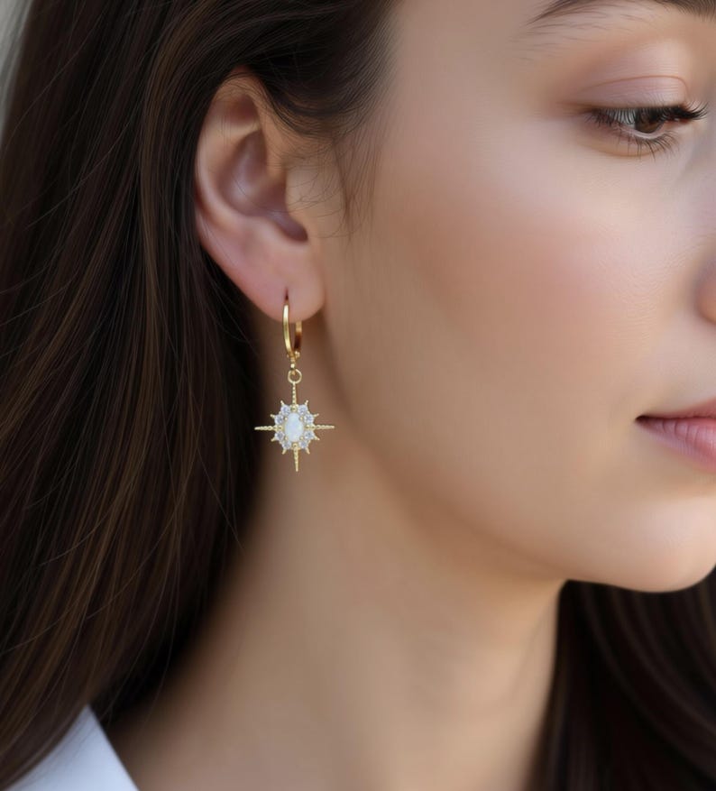 A close-up of a woman's face wearing a pair of gold earrings with a star-shaped gemstone.