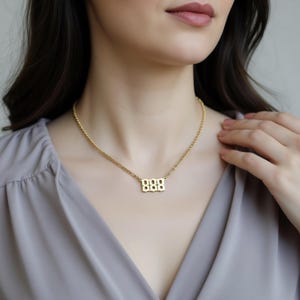 A close-up of a woman wearing a gold necklace with a pendant.