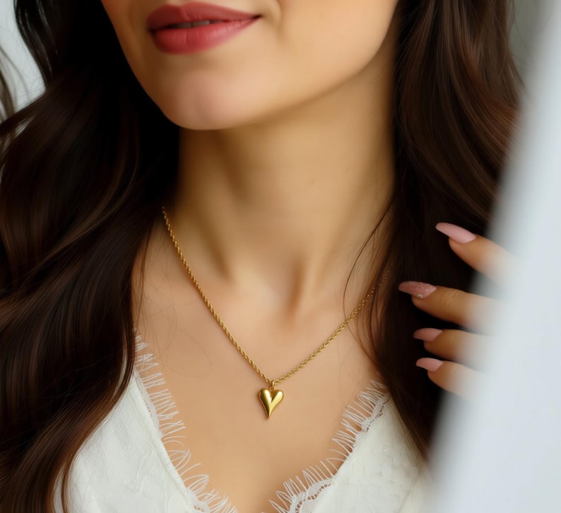 A close-up of a woman's face wearing a gold necklace with a heart-shaped pendant.