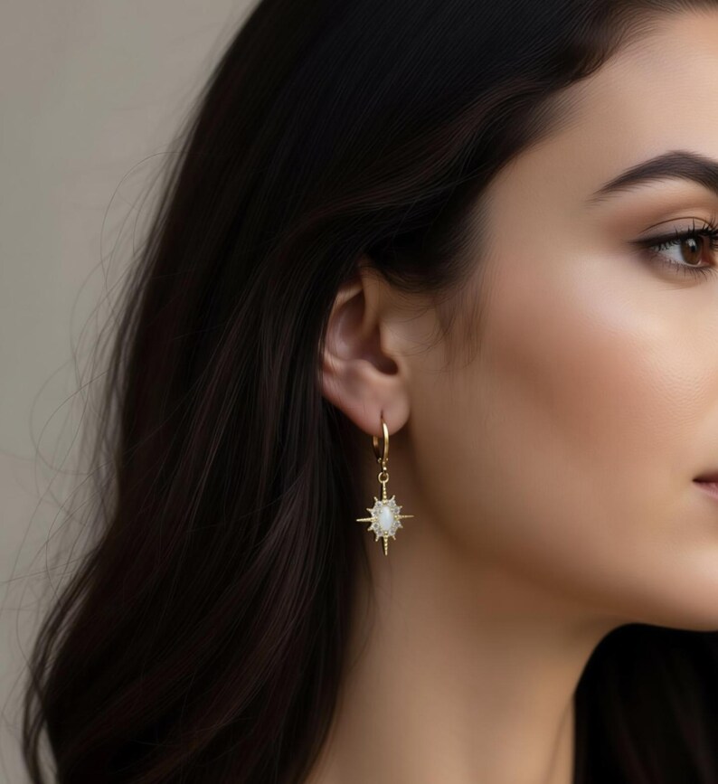 A close-up of a woman's face, focusing on her ear and side profile. She is wearing a pair of gold earrings with a star-shaped pendant.