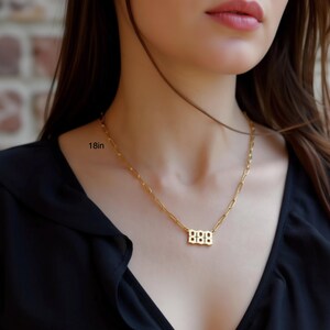 A close-up of a woman wearing a gold necklace with a small pendant.
