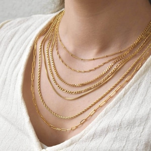 A close-up view of a woman's neck adorned with multiple gold chain necklaces.